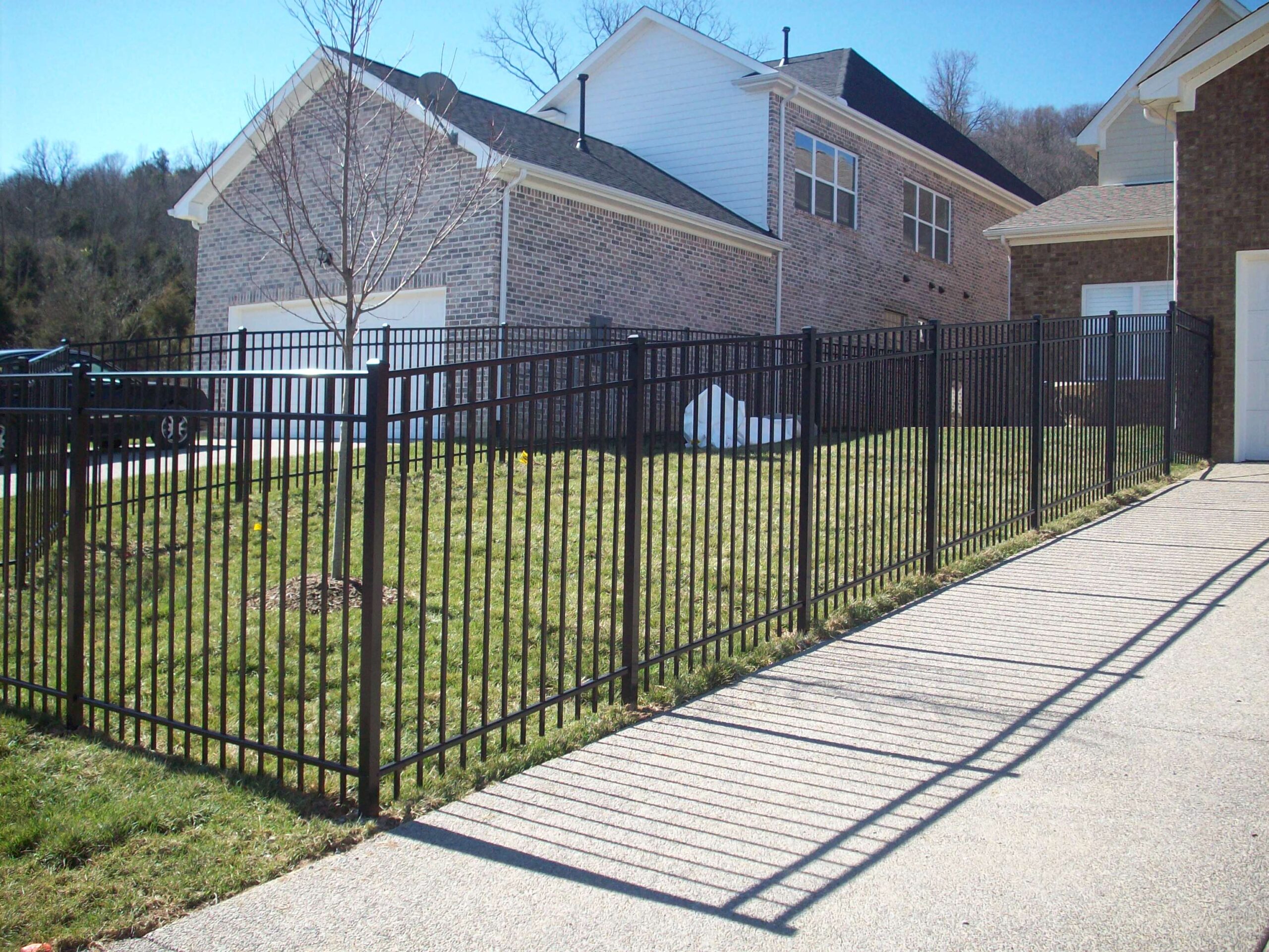 A sleek black ornamental aluminum fence surrounding a yard, offering both security and style.