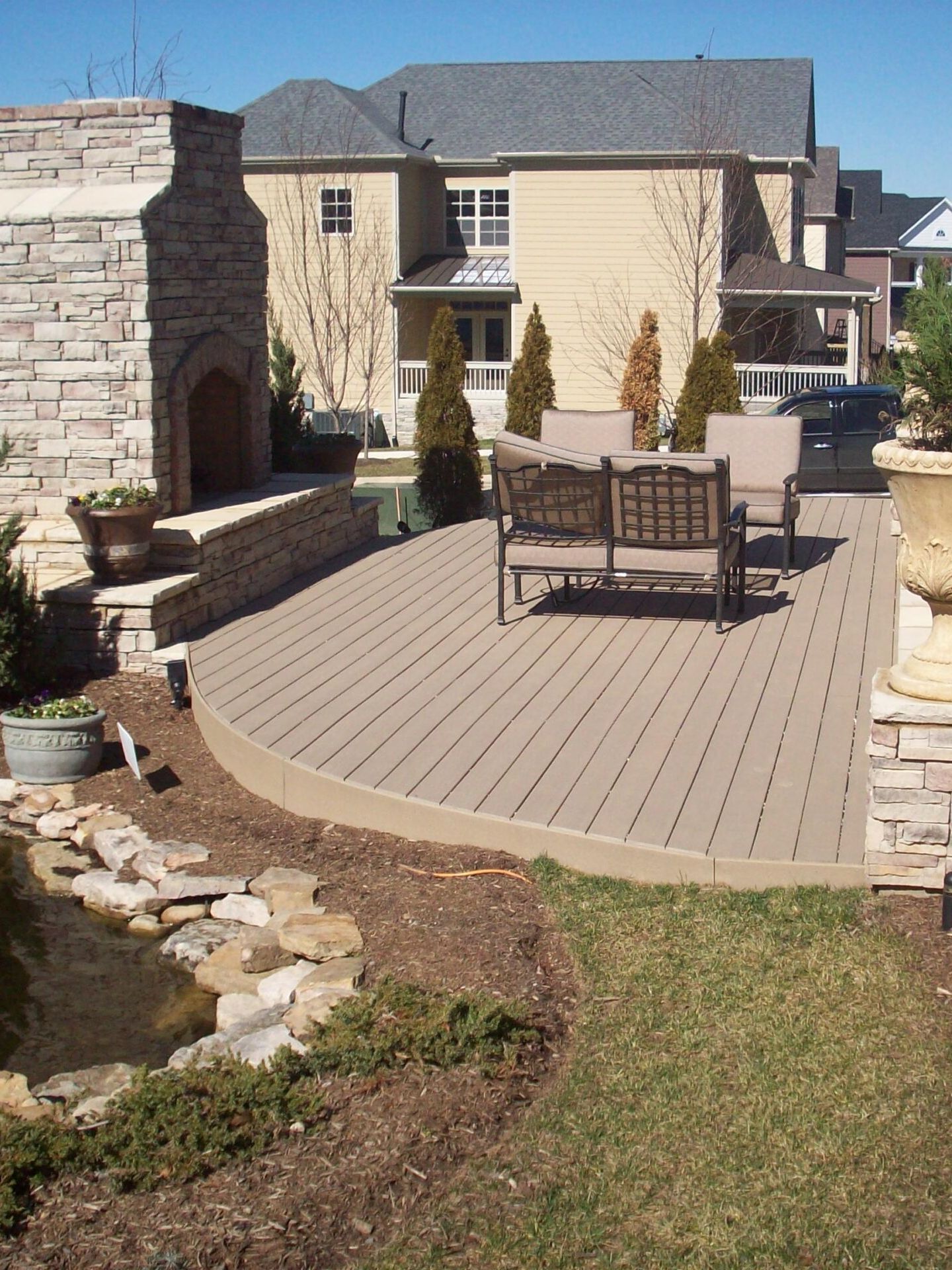 A beautifully designed deck with comfortable seating and a stone fireplace, perfect for outdoor gatherings – built by a Nashville deck builder.