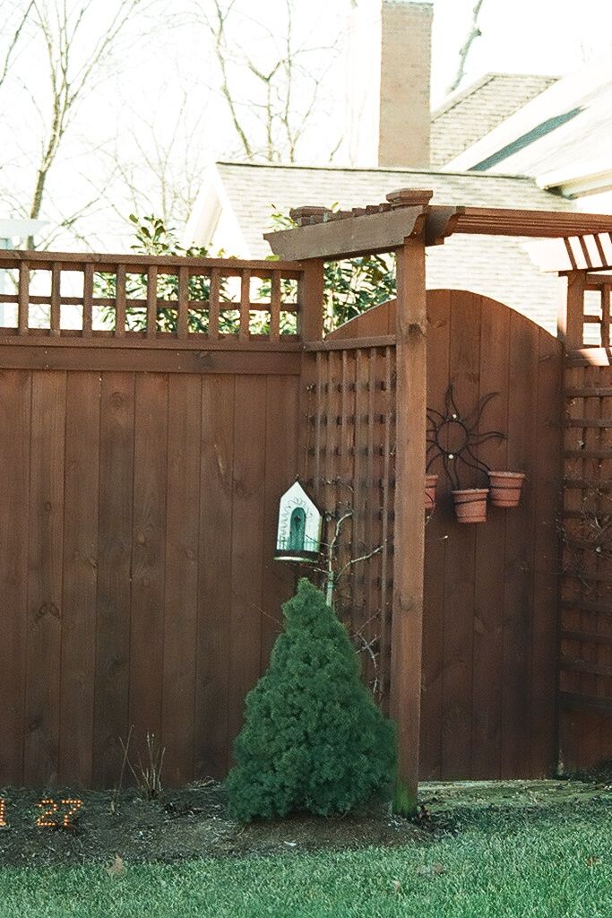 A charming wooden fence with lattice details and a small garden area, designed by a Nashville fence builder